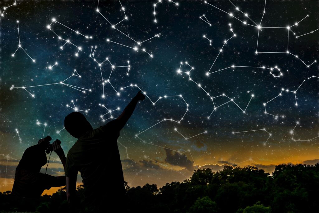 Astrology concept. Constellations on night sky. Silhouettes of astrologers observing zodiac constellation.